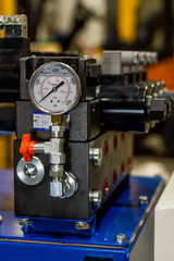 This industrial pressure sensor in a factory is on top a blue box machine used in conveyer systems. This tool helps workers and machinists use their equipment safely.