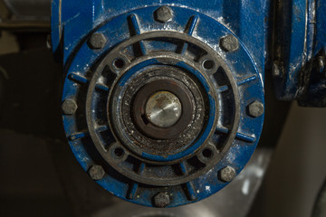 Close up image of blue mechanical pump or drive type industrial metal piece of heavy duty equipment. with metal hoses and built with clean and dirty rusty nuts and bearings 