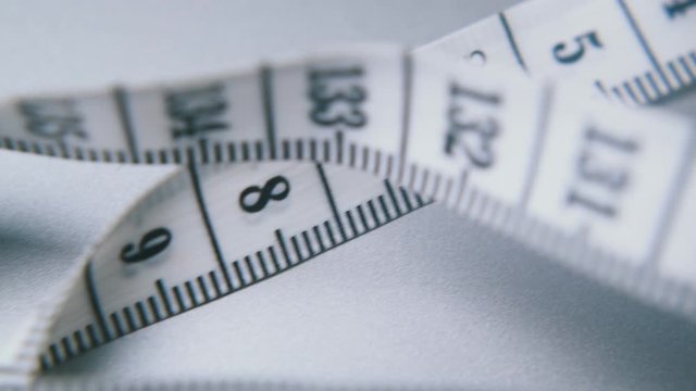 motion above white soft plastic tape measure with centimeter calibration on light grey background extreme close view