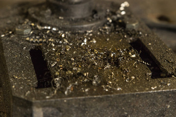 Close up image of the bottom of a milling machine used for drilling holes in metal wood or plastic material. Dirty grimy machine covered in dust dirt and oil used in manufacturing production factory