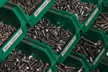 Hundereds of bolts and nuts of various shapes and sizes in green tubs located in a london factory....