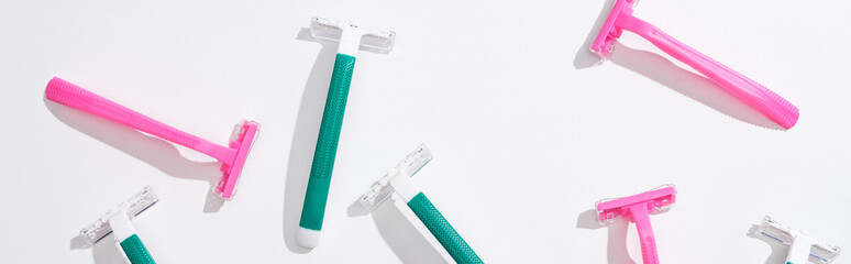 Fototapeta premium top view of female pink and green disposable razors on white background, panoramic shot