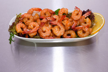 fried shrimp with vegetables and herbs. stainless steel surface