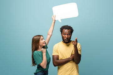 girl holding speech bubble above african american man showing idea gesture on blue background