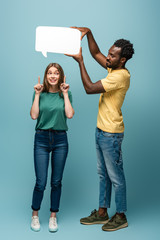 Obraz premium african american man holding speech bubble above girlfriend showing idea gesture on blue background