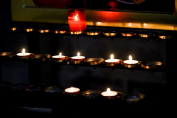 Prayer candles lit inside a church as a votive offering in an act or prayer