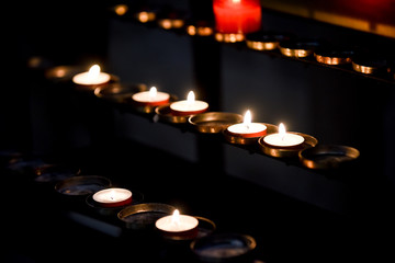 Prayer candles lit inside a church as a votive offering in an act or prayer