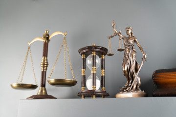 Judge and justice concept. Themis statue, scale and hourglass on off-white background.