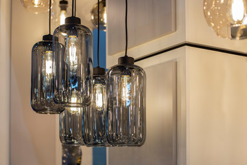 Pendant group of bottle shaped lighters made of dark grey transparent  glass with bulbs inside it. Trendy shandelier for contemporary loft interior