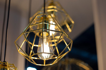 Fototapeta na wymiar Trendy golden geometric pendant lamp with a bulb close up photo with selective focus