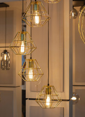 Trendy golden geometric pendant lamp with a bulb  hanging in the chandelier shop