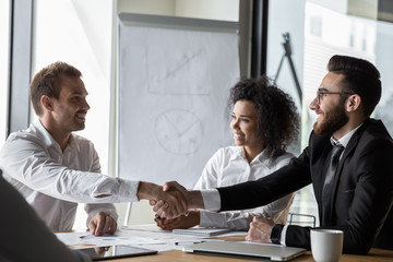 Smiling businessmen handshake closing deal at meeting