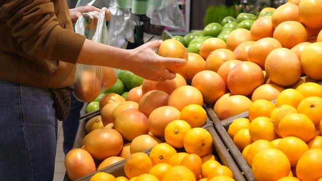 Woman Buying Fresh Fruit At The Supermarket Choosing Grapefruit.