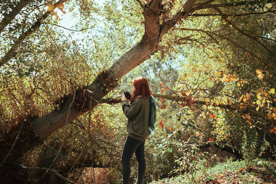 Young woman taking photos in the forest with an old camera