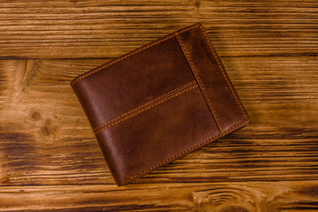 Closed brown leather wallet on wooden table. Top view