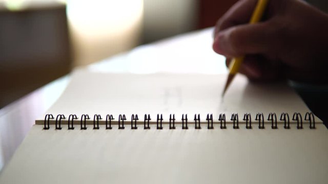 Closeup man hand drag the line on notebook with yellow pencil