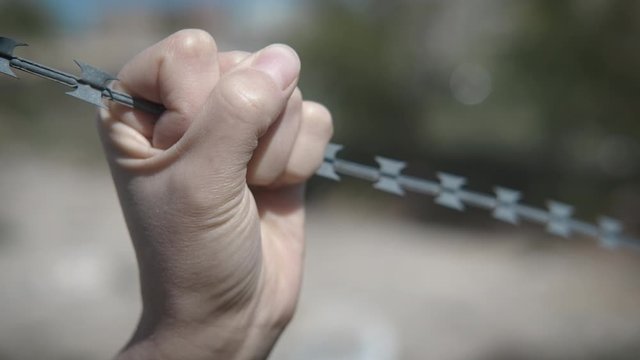 The thirst for freedom. The man clenches the barbed wire in his fist.
