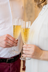 bride and groom with glasses of champagne.couple man and woman in elegant holiday clothes with glasses of champagne in hand in anticipation of the New Year holiday.glasses in people hands. Party or