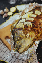 Baked fish river carp with aromatic herbs, spices, salt, vegetables, lemon, garlic, top view,...