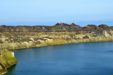 Artificial lake was is formed after the extraction of chalk in an industrial quarry at Krasnoselsky village in the Belarus. Water in open pit between the mountains. Belarusian Maldives