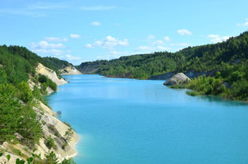 Fototapeta na wymiar Artificial lake was is formed after the extraction of chalk in an industrial quarry at Krasnoselsky village in the Belarus. Turquoise background of the clear ocean water in summer tropical season.