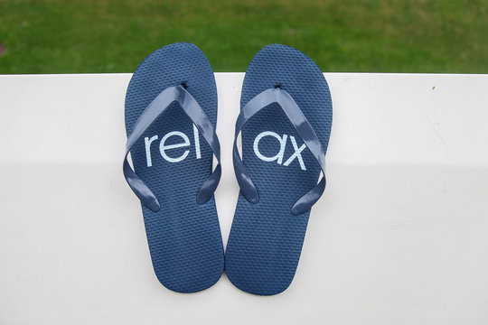 Pair of blue flip-flop with signature of relax pattern on it
