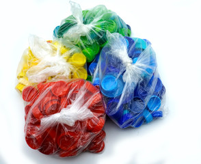 Colorful plastic bottle caps sorted by colors in transparent single use plastic bags. PP an PET pollution.