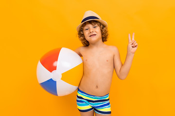 Red-haired boy with a summer hat and a swimming circle on a yellow background
