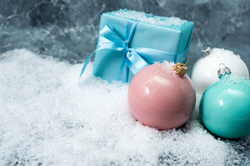 Fototapeta na wymiar christmas balls and gift box on blue snow background