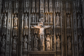 Jesus Christ on the cross in a cathedral or church interior surrounded by ornate stone carvings - obrazy, fototapety, plakaty