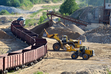 Large heavy front-end loader loading sand it to the freight train.