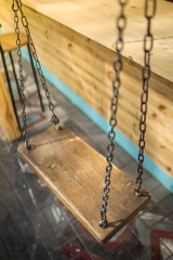 Wooden swing on a chain in a summer cafe.