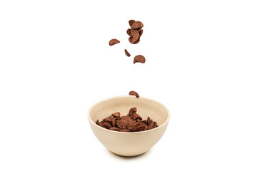 Chocolate corn flakes falling to the white bowl isolated on white. Motion.