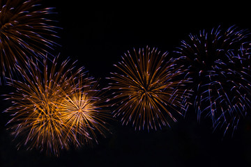 Obraz premium Veriety colorful fireworks on the night sky background. Many flashes of yellow with blue salute. holiday and fun concept