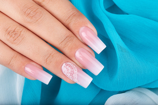 Hand with long artificial manicured nails with ombre gradient design in pink and white colors