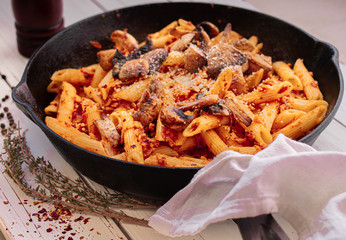 Vegan pasta with mushrooms seitan and herbs on white wooden table