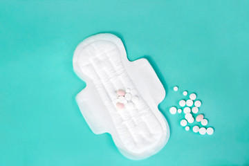 flat lay of feminine hygiene items. Details for critical women's days on a turquoise background. Gaskets for women, health. Analgesic pills