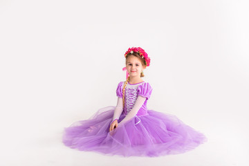 Little blonde girl wearing purple fairy princess dress on white background. Kids costume for new year party