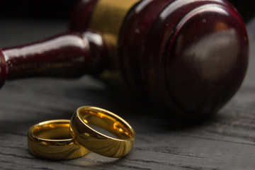 Divorce and separation concept. Two golden wedding rings, judge gavel.