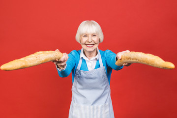Taste of France. Portrait of a joyful senior woman holding a fresh delicious baguette bread smiling...