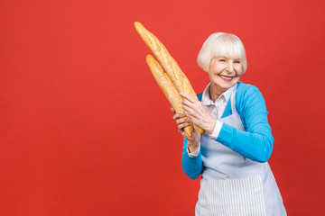 Taste of France. Portrait of a joyful senior woman holding a fresh delicious baguette bread smiling...