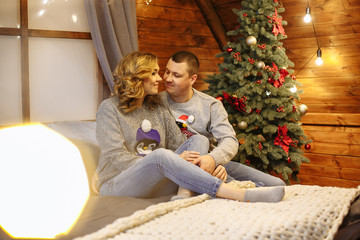 husband and wife in bed next to a christmas tree