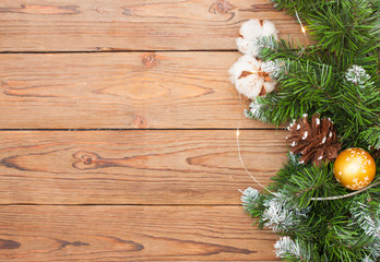 Wooden background with christmas tree, string lights, pines, cinnamon rolls and cotton flowers. 