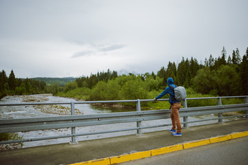 male tourist standing beside the mountain river