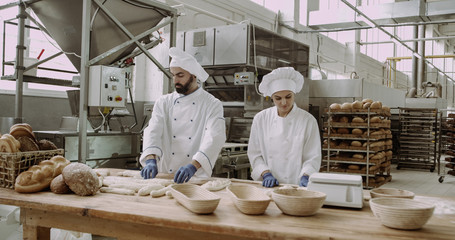 Large capturing video in a big bakery industry industrial machine bakers working on the table preparing dough for bread