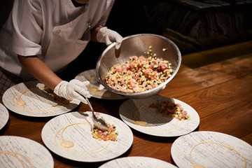 Closeup of professional chef plating dish in restaurant kitchen..