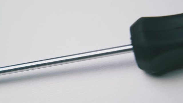 new crosshead screwdriver with red and black plastic handle lies on white background extreme close view