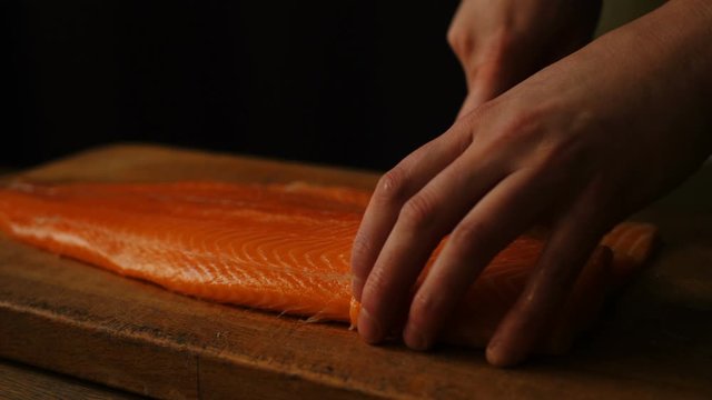 A chef cuts a smoked salmon filet with a knife on a table