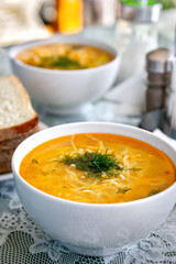 Chicken noodle soup with dill and vegetables in a white plates on the table prepared for dinner. Traditional cuisine. Healthy food.