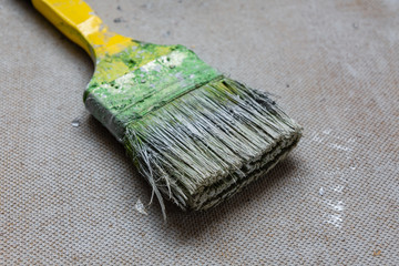 Dirty green paintbrush on a chipboard. House renovation